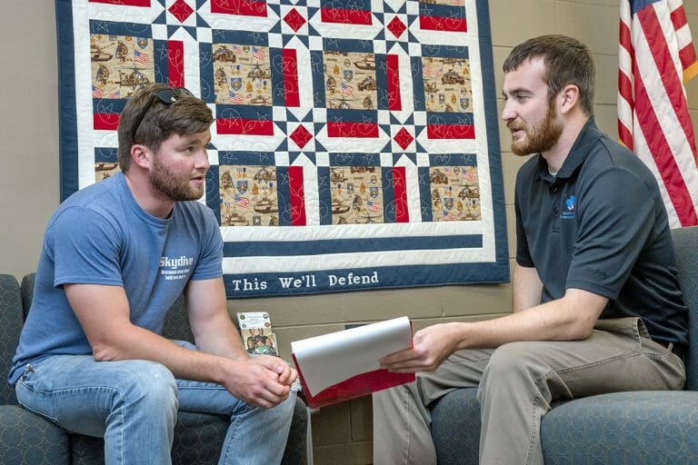Student veteran Kevin Hicks sits with Daniels Center Sean Martin .