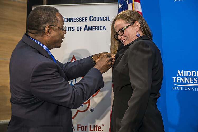 MTSU President Sidney A. McPhee, left, presents Carla Adamson, a lecturer in the Department of Mathematical Sciences, with the President’s Silver Column Award during a surprise presentation Wednesday, March 7, inside Strobel Lobby at MTSU. Adamson was recognized with the special pin for her annual leadership of Merit Badge University. (MTSU photo by Eric B. Sutton)