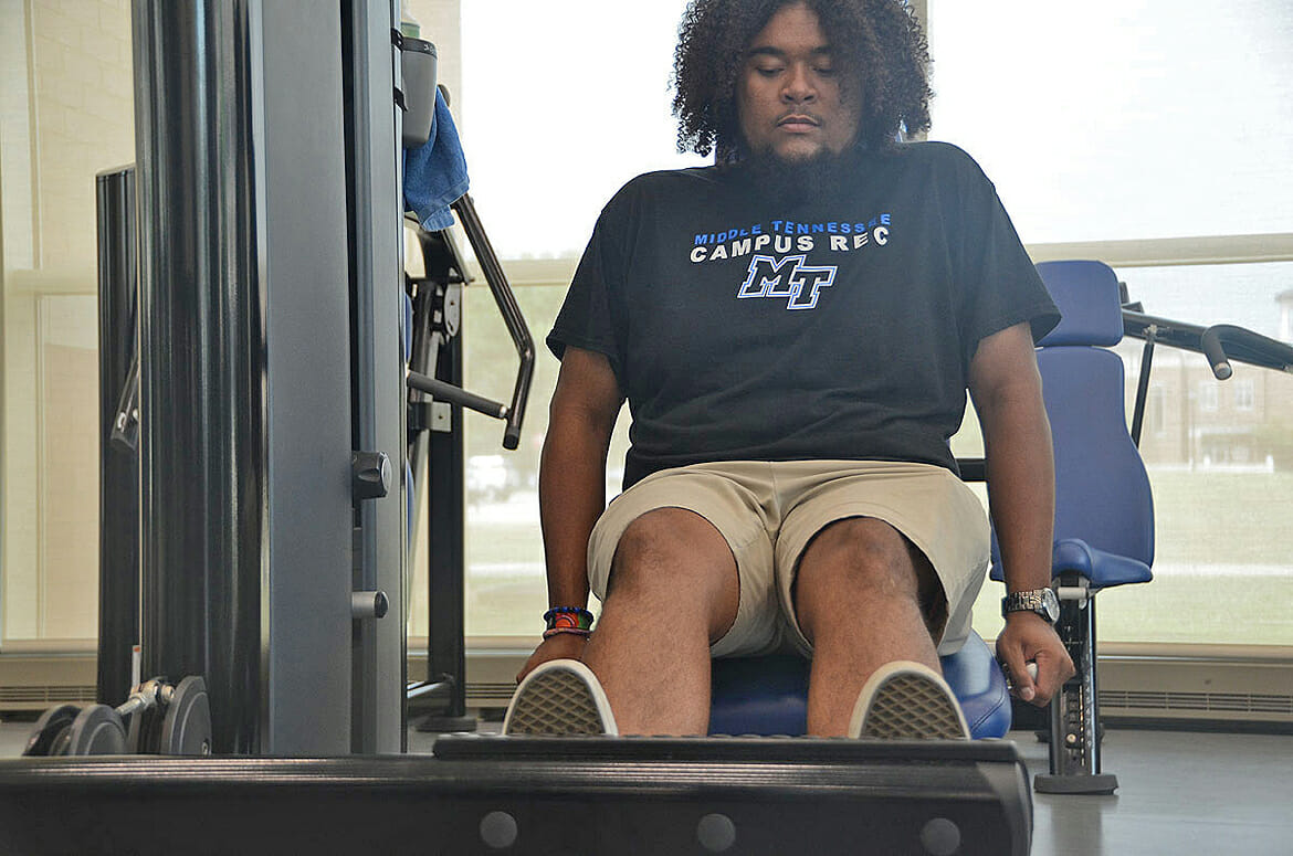 MTSU senior Caleb King of Manchester, Tenn., a supervisor in the weight room inside the MTSU Student Health, Wellness and Recreation Center, works out on one of the Rec’s leg press machines as he moves closer toward reaching his 100-pound weight loss goal. (MTSU photo by K. Simpson)