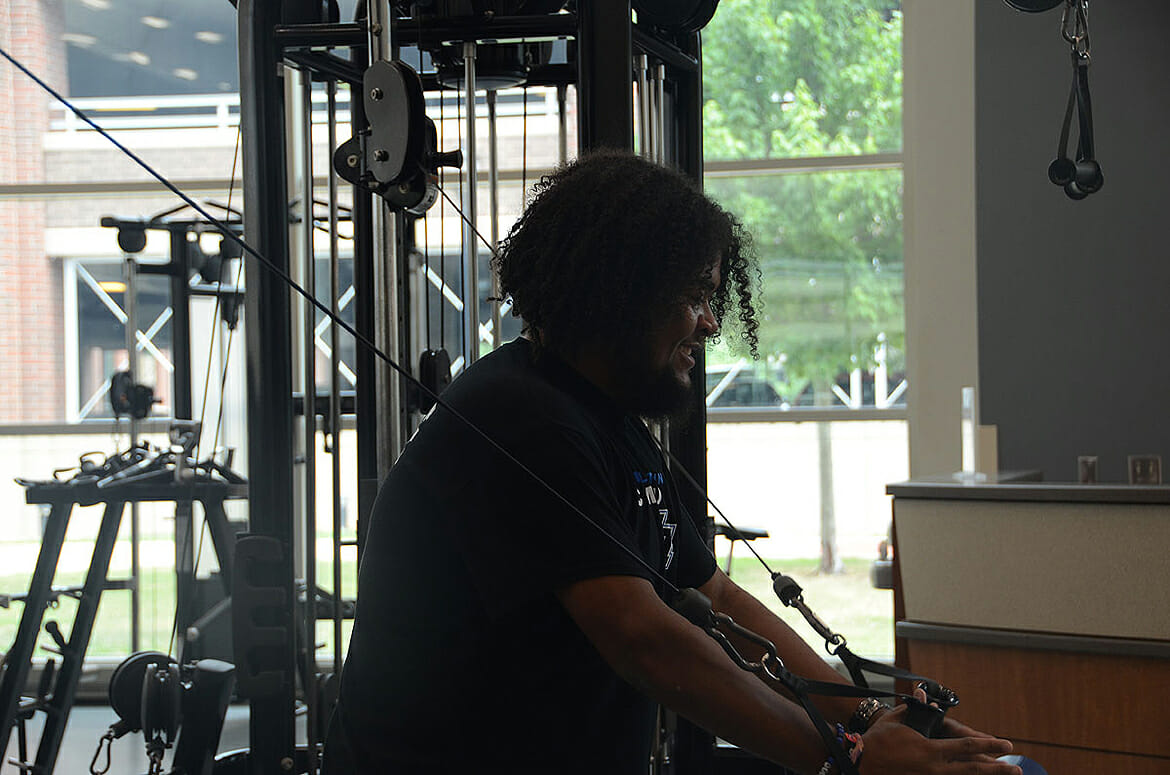 MTSU senior Caleb King of Manchester, Tenn., a supervisor in the weight room inside the MTSU Student Health, Wellness and Recreation Center, works out on the hammer strength high row machine as he moves closer toward reaching his 100-pound weight loss goal. (MTSU photo by K. Simpson)