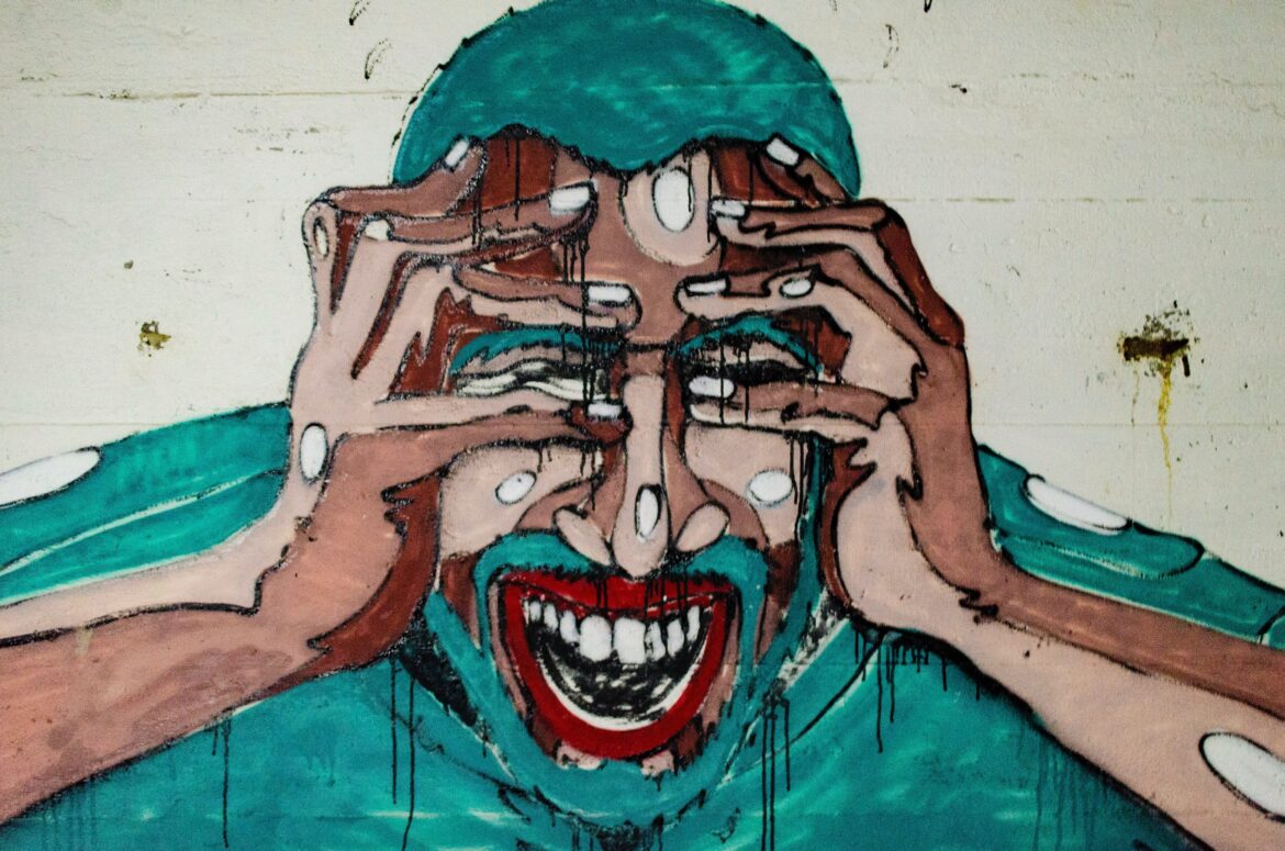 Graffiti art of man yelling and grabbing his head with his hands. Photo by Aaron Blanco Tejedor on Unsplash.