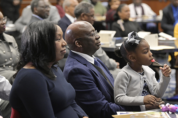 As he holds his daughter, Olivia, in his lap, Frank Michello, MTSU finance professor, center, listens to a tribute before receiving the 2019 John Pleas Faculty Recognition Award at a ceremony held Thursday, Feb. 21, in the Ingram Center at MTSU. The award, given to an outstanding minority faculty member, is named for John Pleas, MTSU Emeritus Professor of Psychology. At left is Michello’s wife, Sonja. (MTSU photo by Andy Heidt)