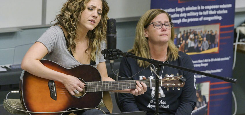 Songwriter Jamie Floyd, left, plays and sings their new song while Jennifer Hyde of Murfreesboro, a U.S. Army mom and executive aide for the dean of MTSU's College of Education, listens at a special showcase for Operation Song's fourth annual “Songs and Stripes” event at MTSU Friday, Oct. 25. The event teams trios of military veterans, student and professional songwriters to create healing music for the veterans and training for the students. Not pictured is co-writer Abby Gibson, a senior commercial songwriting major from Roswell, Georgia. (MTSU photo by Andy Heidt)