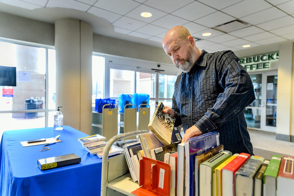 Paul Burt, a circulation assistant in the James E. Walker Library, prepares books in the library vestibule to be checked out as part of the library’s “Pull and Hold” service during the COVID-19 outbreak. (MTSU photo by J. Intintoli)