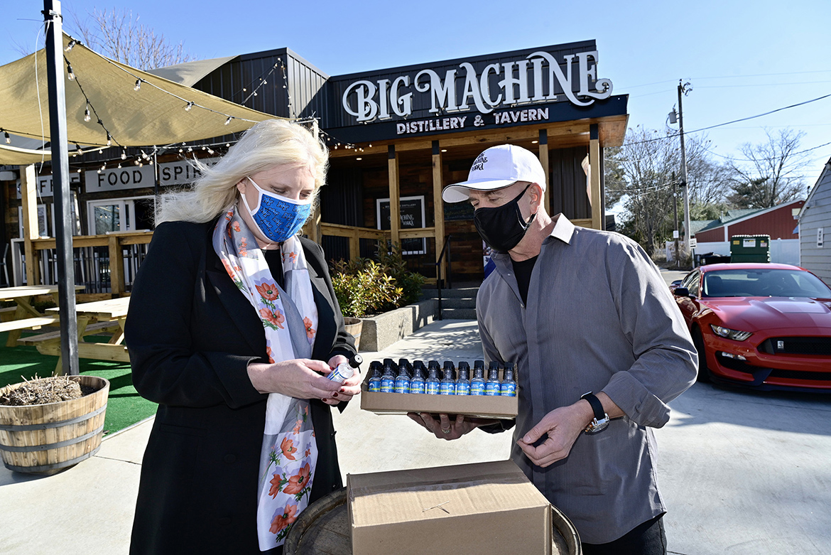 Beverly Keel, dean of MTSU’s College of Media and Entertainment, looks at a bottle of Lightning Hand Sanitizer given to her by Mark Borchetta, executive vice president of Big Machine Vodka outside the distillery’s Nashville, Tenn., location Friday, Jan. 15. MTSU contracted with Big Machine for 6,000 personal-size bottles of sanitizer for students living in on-campus residence halls. (MTSU photo by Andy Heidt)