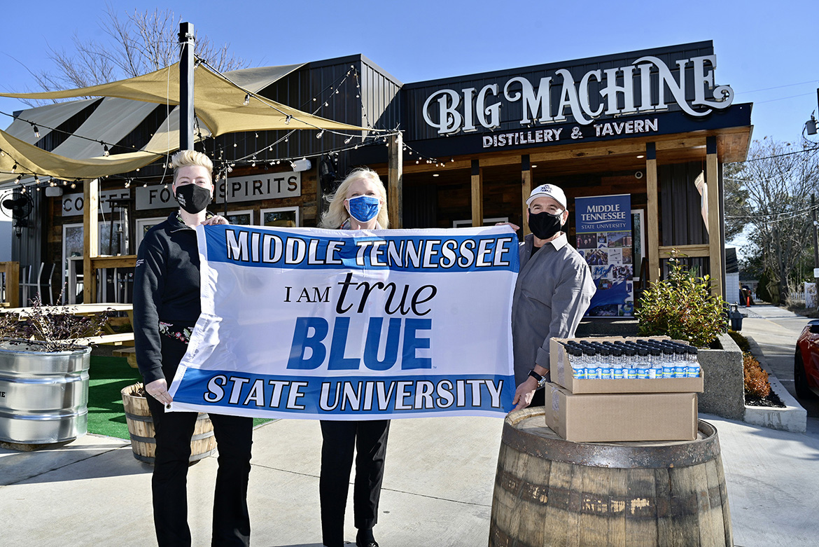 Kiley Judge, general manager of Big Machine Tavern; Beverly Keel, dean of MTSU’s College of Media and Entertainment; and Mark Borchetta, executive vice president of Big Machine Vodka, display an MTSU banner at a presentation Friday, Jan. 15, at the distillery’s Nashville, Tenn., location as MTSU took receipt of 6,000 personal-size bottles of sanitizer made by Big Machine for students living in on-campus residence halls. (MTSU photo by Andy Heidt)
