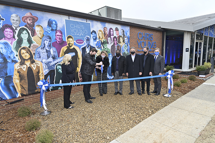 Multiplatinum country entertainer and Murfreesboro, Tenn., native Chris Young, center, cuts an MTSU blue ribbon with help from his mother, MTSU alumna and founding partner at Huskins-Harris Business Management of Nashville Becky Harris, Wednesday, Jan. 27, to celebrate the grand opening of MTSU's Chris Young Cafe. He and Harris are standing in front of a colorful new mural on the north exterior wall of the renovated facility that features more than two dozen MTSU-trained musicians and media members, educators and leaders from throughout the community. Joining them in front of the mural are, from left, Barbara Wolke, senior vice president of the Rutherford County Chamber of Commerce's Convention & Visitors Bureau; Young and Harris; MTSU President Sidney A. McPhee; MTSU Provost Mark Byrnes; John Merchant, chair of MTSU's Department of Recording Industry; and Mark Ezell, commissioner of the Tennessee Department of Tourist Development. (MTSU photo by Andy Heidt)