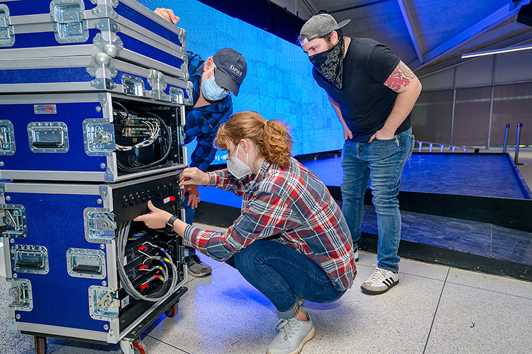 MTSU student Hannah Humphress, a Knoxville, Tenn., senior majoring in audio production, adjusts a connector for the custom LED video wall behind the stage of the university's new Chris Young Cafe in preparation for a special livestreamed grand opening on Wednesday, Jan. 27. Looking on are, at left, Frank Baird, assistant professor of audio production and the cafe's new director, and Jon White, a graduate teaching assistant in the Department of Recording Industry's Master of Fine Arts in Recording Arts and Technologies Program. Chris Young, a former MTSU student turned multiplatinum country entertainer, donated $50,000 to help renovate the 1963-era cafeteria into a teaching and rehearsal space and performance venue for the College of Media and Entertainment. (MTSU photo by J. Intintoli)