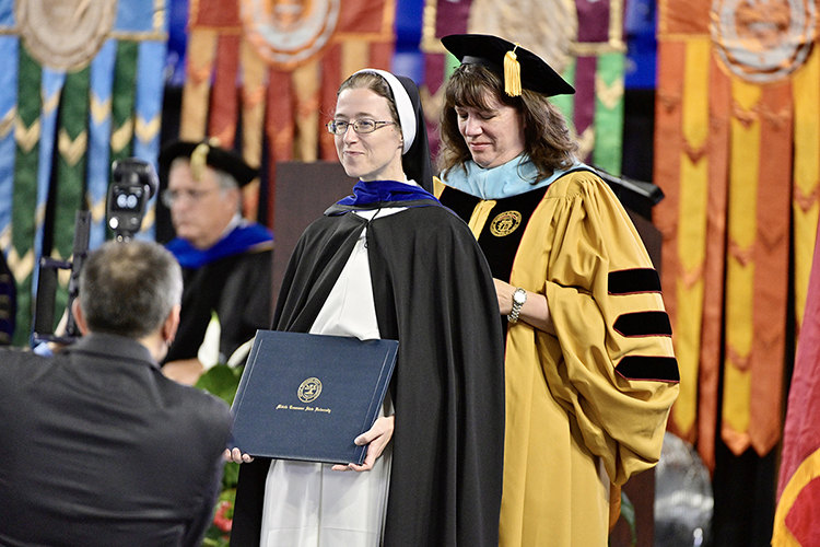 Sister Cecelia Ann Wanner, left, president of Aquinas College in Nashville, smiles gently as MTSU mathematical sciences professor Alyson Lischka carefully adjusts the academic hood around Wanner's neck and shoulders to signify completion of her doctoral degree in math and science education at MTSU's summer 2021 commencement ceremony Saturday, Aug. 7, in Murphy Center. MTSU presented degrees to 825 new graduates of the August Class of 2021 at the event. (MTSU photo by Andy Heidt)