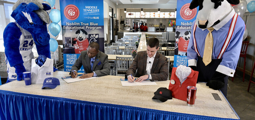 With their respective mascots looking on, MTSU President Sidney A. McPhee, seated left, and Beau Noblitt, restaurant operator for Chick-fil-A Murfreesboro, sign an agreement Wednesday, Jan. 12, at the fast-food chain’s Memorial Boulevard location that provides tuition assistance for qualifying local employees. (MTSU photo by Andy Heidt)