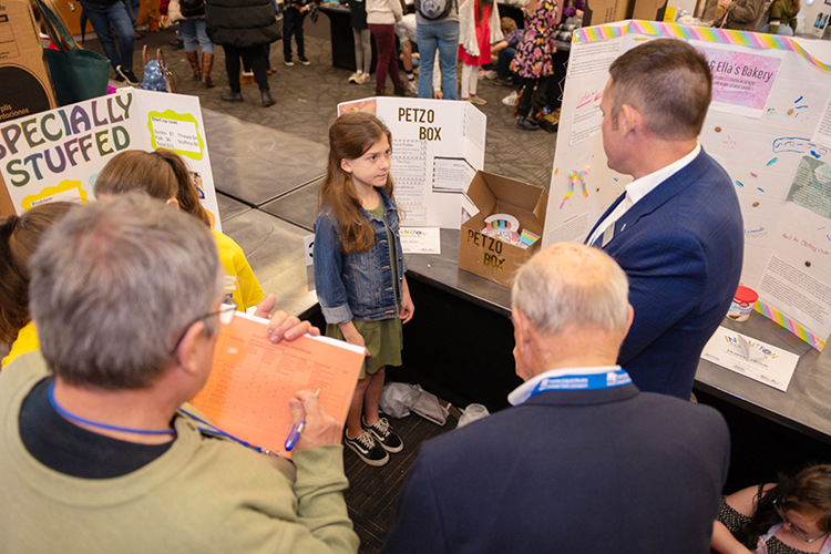 Andie Hutto, center, a fifth grader at Coles Ferry Elementary School in Lebanon, Tenn., listens carefully to a question from Josh Aaron, right, a professor in MTSU's Department of Marketing in the Jones College of Business, about her invention to "make life easier" at the 29th annual Invention Convention in the Student Union Ballroom Thursday, Feb. 17. Aaron, the marketing department's Pam Wright Chair of Entrepreneurship, served as one of more than 20 judges for inventions by 700-plus fourth-, fifth- and sixth-grade students from 36 schools across the Midstate to make life easier, their newly invented games and their entrepreneurship plans for their projects. (MTSU photo by James Cessna)