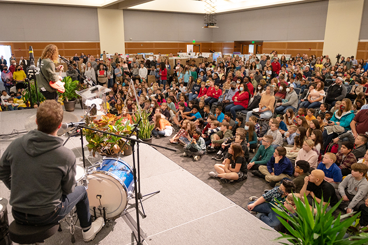 Invention Convention 2022 participants, their teachers and supporters listen carefully inside MTSU's Student Union Ballroom Thursday, Feb. 17, as musicians Jacob Schrodt, seated in the foreground, and Toby Friesen, standing at center left, talk about the inventions that help them play their drums and guitar, respectively. The guest speakers were part of the 29th annual event that welcomed 700-plus fourth-, fifth- and sixth-grade students from 36 schools across the Midstate to showcase their inventions to make life easier, their newly invented games and their entrepreneurship plans for their projects. (MTSU photo by James Cessna)