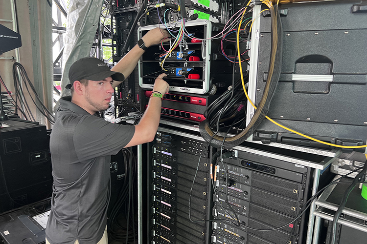 Justin Tart, a senior majoring in video and film production from Lebanon, Tenn., checks equipment Wednesday, June 15, behind The Other stage in preparation to provide video and streaming services for upcoming performances at the 2022 Bonnaroo Music and Arts Festival June 16-19 in Manchester, Tenn. (MTSU photo by Andrew Oppmann)