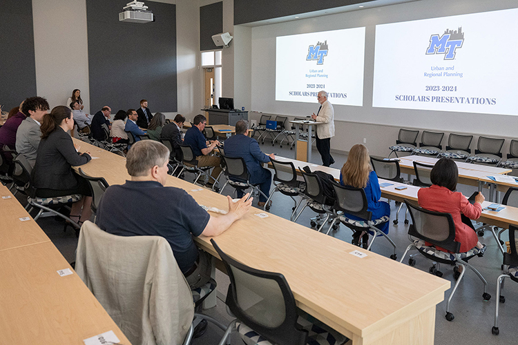 Paul Martin Jr., chair of the Jennings and Rebecca Jones Chair of Excellence in Urban and Regional Planning, standing right, addresses attendees to research presentations by the inaugural cohort of the chair’s Scholars Program within the Jones College of Business at Middle Tennessee State University. This May 3 year’s program concluded with the scholar presentations inside the Academic Classroom Building on the MTSU campus in Murfreesboro, Tenn. (MTSU photo by Andy Heidt)