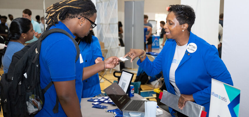 A Middle Tennessee State University student takes a business card from Chundra Davis, talent acquisition specialist from electric vehicle battery maker Ultium Cells, one of the 235 companies attending the Career Development Center’s 2024 Big Career Fair on Thursday, Sept. 26, inside the Campus Recreation Center in Murfreesboro, Tenn. (MTSU photo by James Cessna)