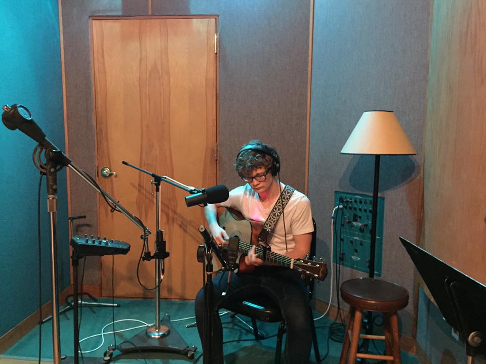 Cooper Gilliam, a Commercial Songwriting major, plays his guitar in a small recording studio room 