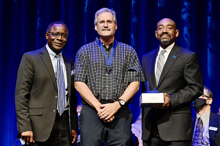 MTSU marketing professor Timothy Graeff, center, proudly wears his new Career Achievement Award medallion Thursday, Aug. 19, after receiving the university's top teaching honor from President Sidney A. McPhee, left, and alumnus Ronald Roberts, vice president of the MTSU Foundation in Tucker Theatre during the 2021 Fall Faculty Meeting. Graeff also is founder of MTSU’s Office of Consumer Research. Ten more MTSU professors also were recognized by the MTSU Foundation with awards for their for their accomplishments in and outside the classroom, and McPhee presented his 2021 State of the University address during the gathering. (MTSU photo by Andy Heidt)