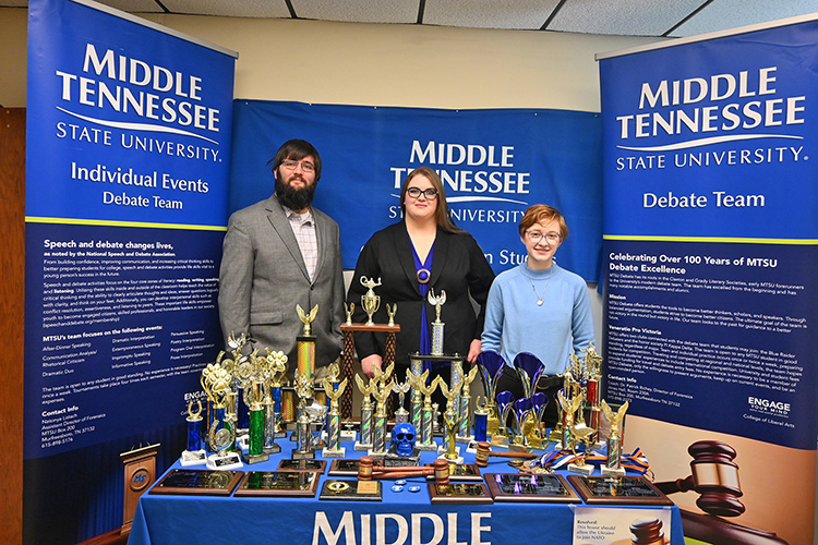 From left, Blue Raider Debate members Derek Dismukes, a spring graduate in criminal justice administration and pre-law minor; rising senior Jessica Rogers, a psychology and communication studies major; and Elliot Certain, a rising senior social work major with an honors minor, are pictured in Jones Hall at Middle Tennessee State University with the collection of trophies and awards captured by individual members and the team during the 2022-23 debate season. (MTSU photo by Jimmy Hart)