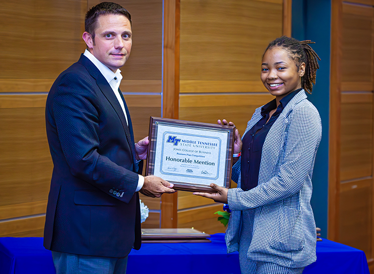 Alexis Mahon, right, a senior political science and pre-law major from Memphis, Tenn., accepts her honorable mention plaque from Joshua Aaron, chairholder of the Wright Chair of Entrepreneurship and competition organizer, at the 2023 Business Plan Competition Finals held April 26 in the Student Union Parliamentary Room at Middle Tennessee State University. As a finalist, Mahon earned a $2,000 prize for her plan for the She-Ssentials cosmetics company. (MTSU photo by Tom Beckwith)