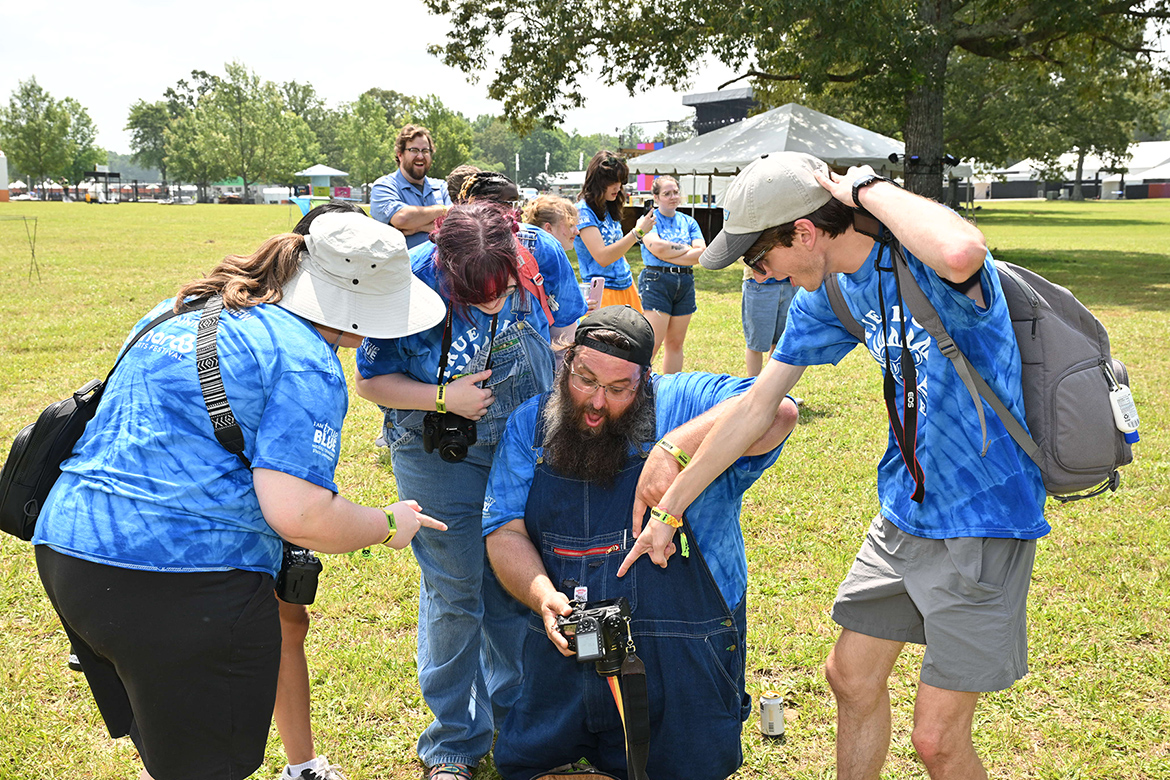 Jonathan Trundle, center, associate professor and coordinator of photography at Middle Tennessee State University in Murfreesboro, Tenn., and a small group of MTSU students react to an image on his camera Wednesday, June 11, at the 2025 Bonnaroo Music and Arts Festival in Manchester, Tenn. As part of its annual visit to the event, the university has a team of about 50 students, with support from a small group of faculty and staff, getting hands-on experience filming and livestreaming concerts and reporting stories on deadline during the four-day event. (MTSU photo by James Cessna)