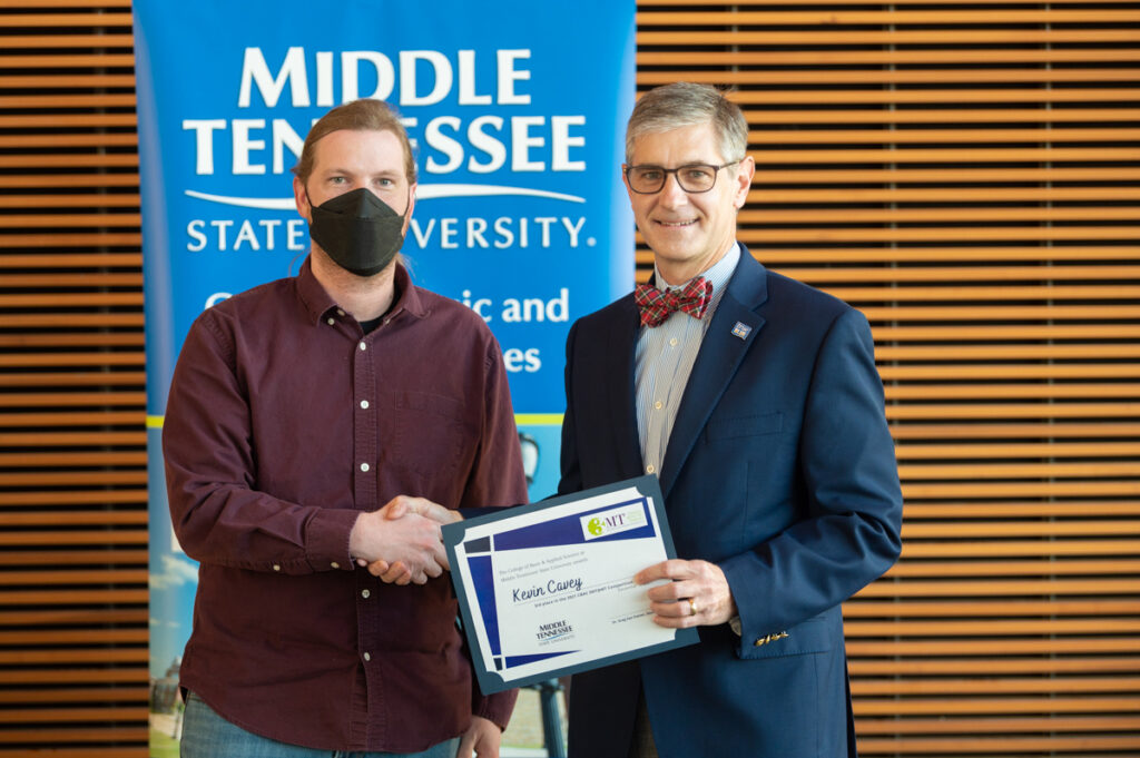 Doctoral candidate Kevin Cavey, left, shakes hands with Greg Van Patten, College of Basic and Applied Sciences interim dean. Cavey placed third and received $300 in the first 3MT@MT research video competition recently in the Science Building. (MTSU photo by James Cessna)