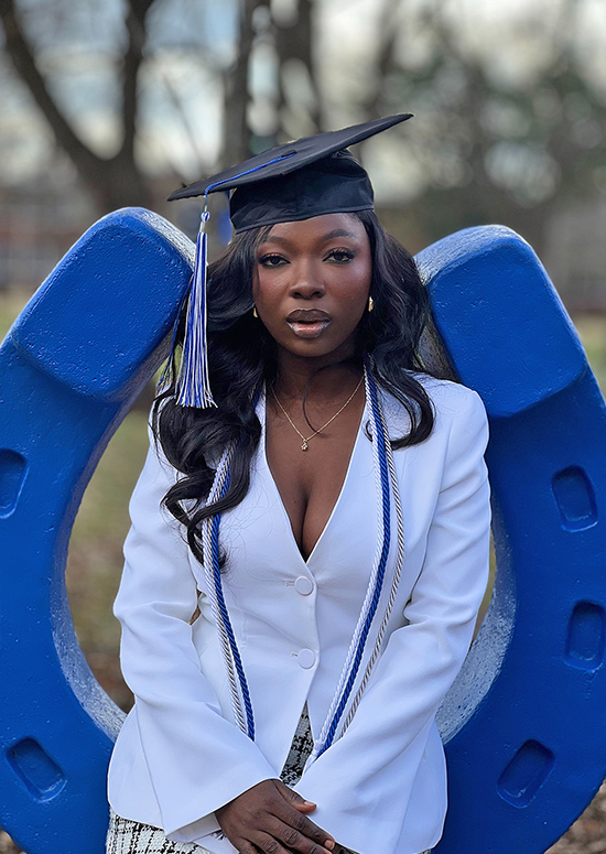 Middle Tennessee State University Fall 2024 graduate Bolade Onafuye, of Nigeria, poses with the infamous MTSU blue horseshoe in Walnut Grove on campus in Murfreesboro, Tenn., while donning her cap and Experiential Learning Scholar cords. A health care informatics master’s major and honorary Phi Kappa Phi Honor Society member, Onafuye is the first student from her program to complete an EXL project that has developed a deep community impact. (Submitted photo)