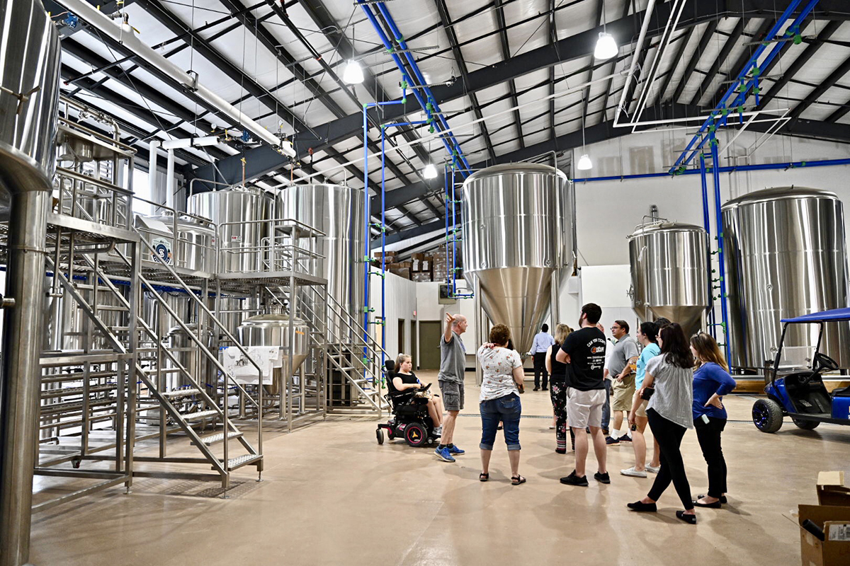 On a tour of the Hop Springs facility Thursday, May 23, visitors learn about the brew house on the left and the large fermentation and regular tanks in the room. MTSU and Hop Springs celebrated with a grand opening of the facility. (MTSU photo by J. Intintoli)