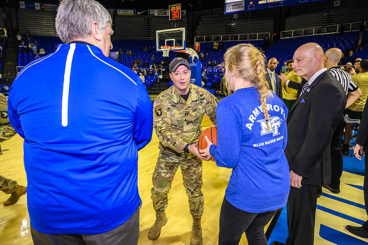 An instructor from The Sabaulaski Air Assault School, 101st Airborne Division (Air Assault), second from left, delivers the MTSU-Marshall game ball in Murphy Center to an MTSU ROTC student in January 2019 as athletics director Chris Massaro, left, and Keith M. Huber, a retired lieutenant general with a 38-year military career and MTSU’s senior adviser for veterans and leadership initiatives, observe. Members of the 101st return Thursday, Jan. 30, with a featured rappelling demonstration by the Screaming Eagle soldiers before the MTSU Lady Raiders game against UTEP in Murphy Center during Blue Raider Veteran and Military Appreciation Night. The soldiers learn the craft at The Sabalauski Air Assault School at Fort Campbell. (MTSU file photo by Eric Sutton)