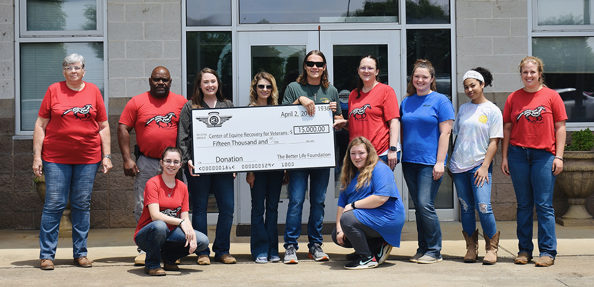 Wearing their special red T-shirts, members of the Murfreesboro, Tenn.-based Veteran Recovery Center attend the recent check presentation to help fund the MTSU Center of Equine Recovery for Veterans, or CERV, at the MTSU Horse Science Center on West Thompson Lane. Brad Arnold, who is helping to hold the check and frontman for the rock band 3 Doors Down, brought a $15,000 donation from the band’s Better Life Foundation. (Submitted photo)