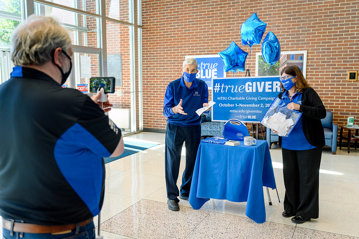Marketing Director David Foster from the Division of Marketing and Communications records John Hood, former state representative and current director of Community Engagement and Support, and Brenda Wunder, executive secretary for Facilities Services, in the Cope Administration Building atrium as they announce the winners of a weekly Employee Charitable Giving Campaign prize giveaway in late October. (MTSU photo by J. Intintoli)
