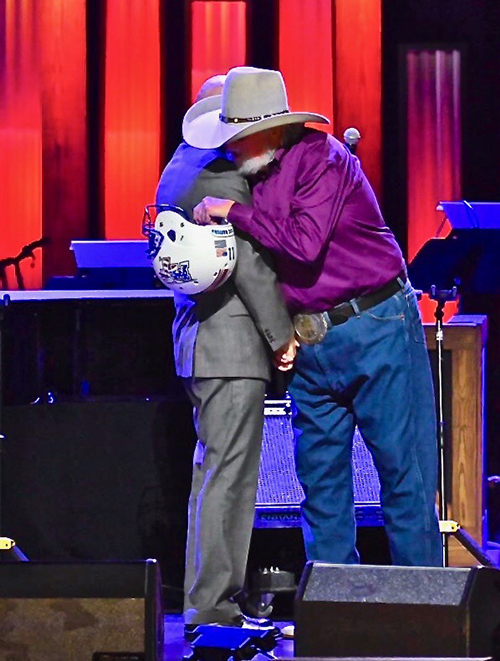 Country Music Hall of Famer Charlie Daniels, namesake and patron of MTSU’s Charlie and Hazel Daniels Veterans and Military Family Center, embraces retired Army Lt. Gen. Keith Huber after Huber presented him a Blue Raider Football helmet. Huber surprised Daniels during an Oct. 15 show at the Grand Ole Opry in Nashville, Tenn. (MTSU photo by Cat Curtis Murphy)