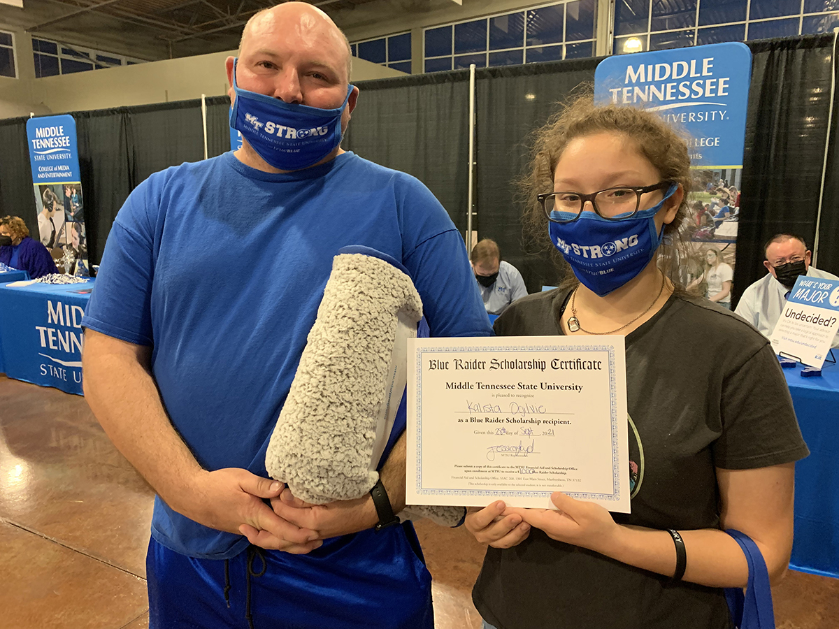 Kalista Ogilvie, right, of Clarksville, Tenn., received a $1,500 scholarship from MTSU President Sidney A. McPhee and her stepfather, Andrew Sims, won an MTSU blanket by attending the university’s True Blue Tour event Tuesday, Sept. 28, at the Wilma Rudolph Event Center. Ogilvie is highly interested in MTSU’s horse science, theater and arts programs. (MTSU photo by Randy Weiler)