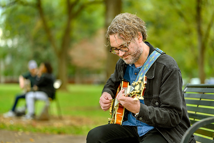Professional musician and returning student Adam Davis, whose studying jazz in MTSU's Master of Music program, picks his guitar in Walnut Grove during the fall 2021 semester. (MTSU photo by J. Intintoli)