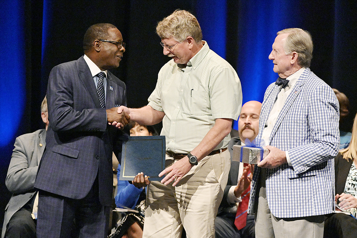 MTSU physics professor William Robertson, center, accepts the 2019 Career Achievement Award from university President Sidney A. McPhee, left, and MTSU Foundation President Ron Nichols during the annual Fall Faculty Meeting held Thursday, Aug. 22, in Tucker Theatre. (MTSU photo by Andy Heidt)