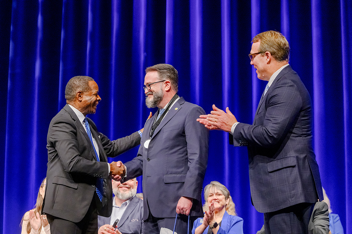 Philip Phillips, center, associate dean of the Middle Tennessee State University Honors College and English professor, is congratulated by university President Sidney A. McPhee, left, and Brian Kidd, president of the MTSU Foundation, for being this year’s recipient of the university’s top faculty award, the Career Achievement Award, during the 2025 Fall Faculty and Staff Meeting held Thursday, Aug. 21, inside Tucker Theatre on the MTSU campus in Murfreesboro, Tenn. (MTSU photo by Andy Heidt)