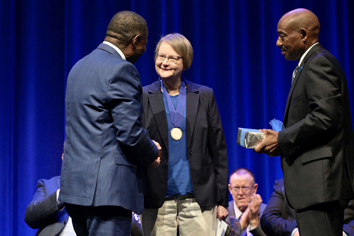 Middle Tennessee State University President Sidney A. McPhee, left, congratulates MTSU Department of Management professor Jill Austin, recipient of the 2023 Career Achievement Award, as Ronald Roberts, president of the MTSU Foundation, prepares to give her a gift on stage at Tucker Theatre during the annual Fall Faculty Meeting on Thursday, Aug. 24. Austin has spent 38 years at MTSU, where she has served as chair of the Department of Management and president of the Faculty Senate. (MTSU photo by Andy Heidt)