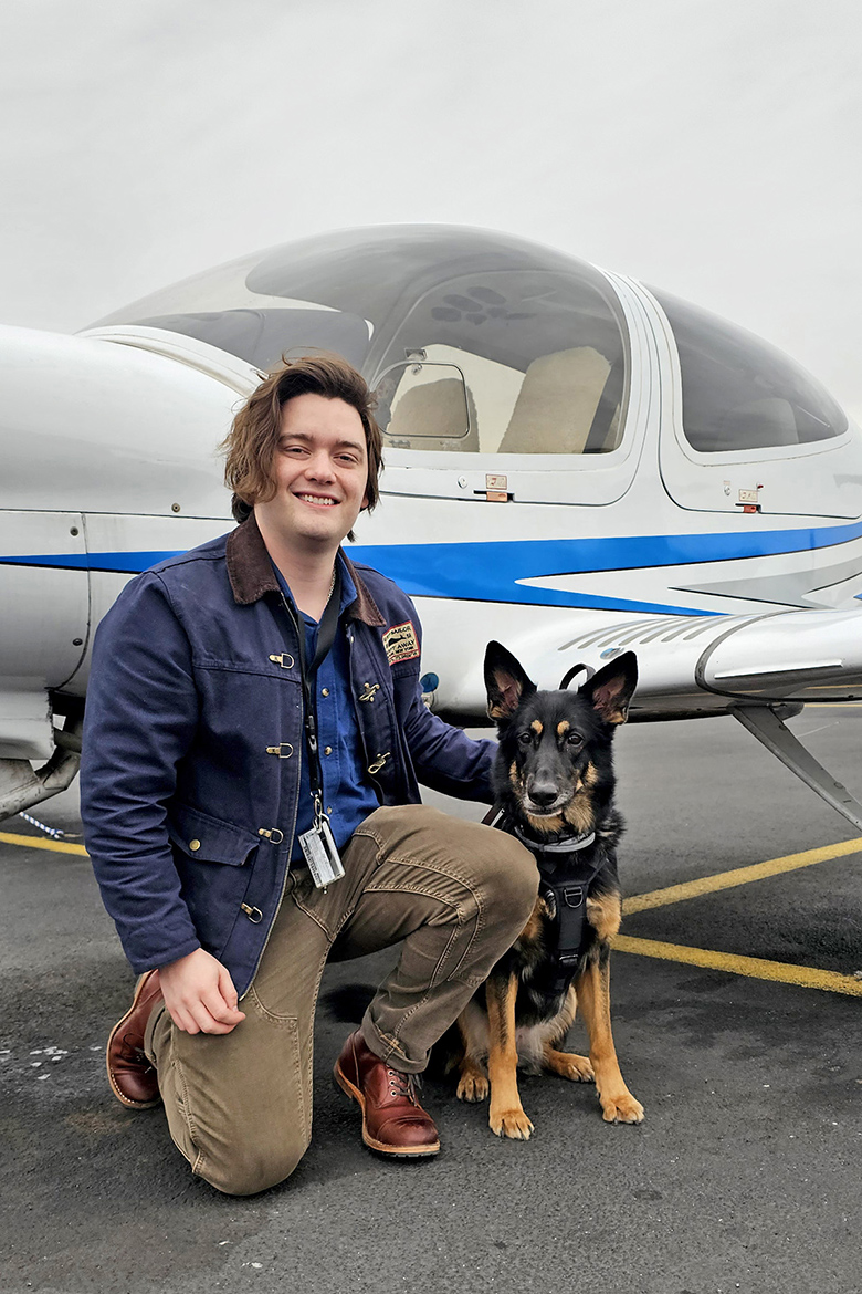 In this spring 2025 semester photo, Middle Tennessee State University aerospace major John Farris, of Columbia, Tenn., sits beside an MTSU plane with Ellie, the service dog he is currently training, at the Murfreesboro, Tenn., Municipal Airport. (MTSU photo by Robin E. Lee)