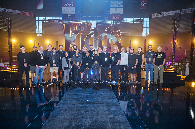 Middle Tennessee State University Department of Media Arts students, faculty and alumni pose for a photo in front of the stage of “The Judds: Love is Alive – The Final Concert” event, for which they helped provide the broadcast and production, on Nov. 3, 2022, at the university’s Murphy Center. MTSU media arts professor Bob Gordon, seventh from the right, produced a red-carpet broadcast before the made-for-TV concert, which is set to air Saturday, April 29, on CMT. (MTSU file photo by James Cessna)