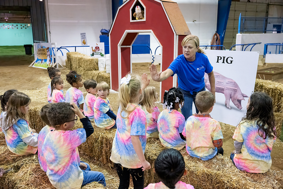 Middle Tennessee State University School of Agriculture instructor Alanna Vaught, standing right, gives a girl a high five before explaining to the group about the Little Acres fruit and vegetable area they are about to enter Tuesday, April 15, during the annual Ag Ed Spring Fling in the MTSU Tennessee Livestock Center on the campus in Murfreesboro, Tenn. (MTSU photo by Andy Heidt)