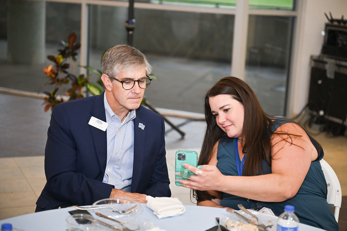 Middle Tennessee State University alumna Rebecca Carroll, right, of Chattanooga, Tenn, shows MTSU College of Basic and Applied Sciences’ Dean Greg Van Patten a cell phone photo following dinner on Wednesday, June 26, Day 1 of the 15th annual Alumni Summer College in the second-floor atrium in the Miller Education Center on Bell Street in Murfreesboro, Tenn. A graduate from the Class of 2002, Carroll earned a bachelor’s degree in anthropology. She is a senior digital marketing specialist at PMD Group. (MTSU photo by James Cessna)