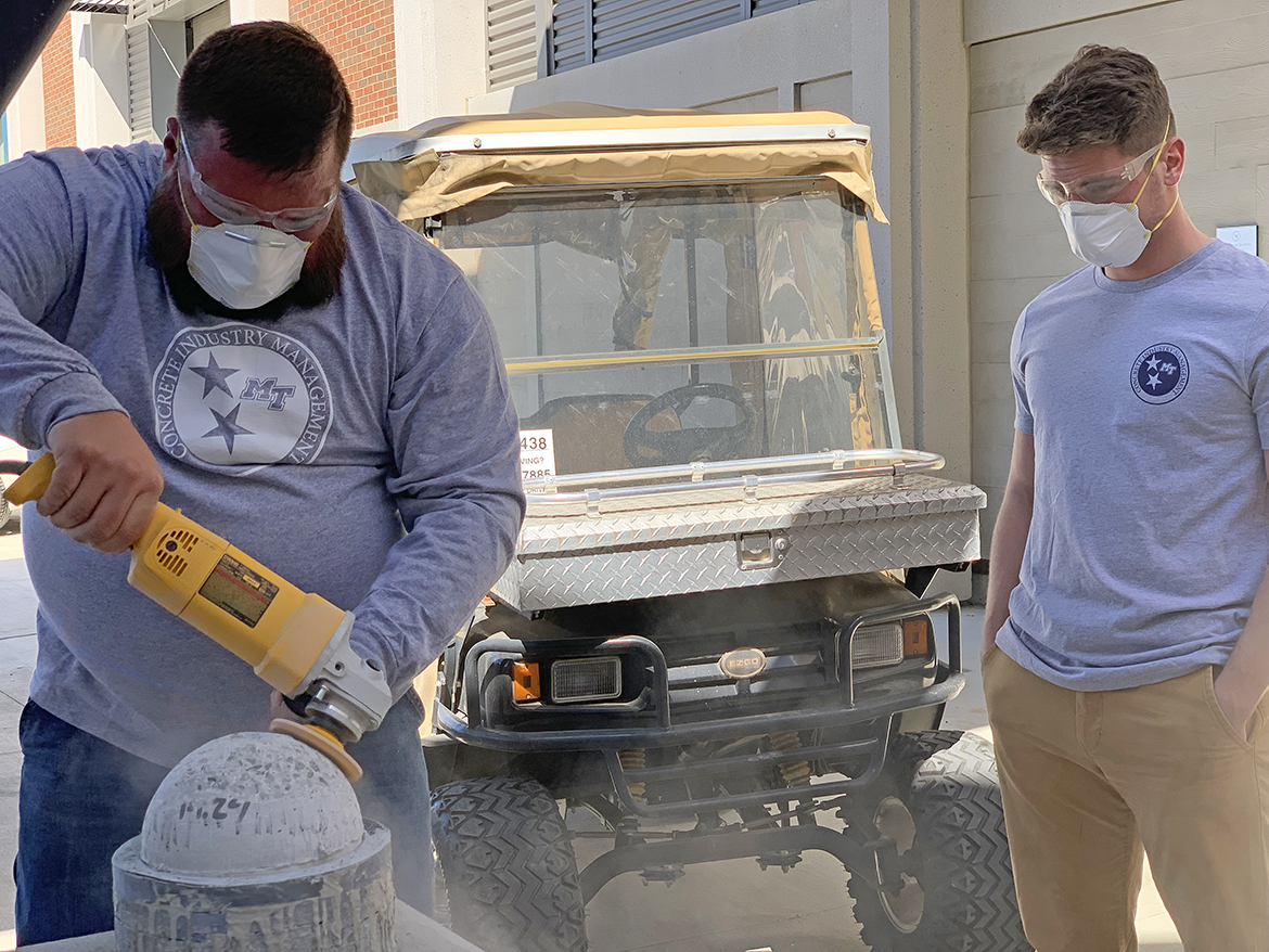 Middle Tennessee State University Concrete Industry Management junior Jerry Stewart of Murfreesboro, left, smooths the rough edges off a concrete bowling ball as fellow junior Christian Denton of Medina, Tenn., observes recently outside the School of Concrete and Construction Management Building CIM laboratory. Six MTSU students will take their best two concrete bowling balls to the 2023 American Concrete Institute’s Student Fiber-Reinforced Concrete Bowling Ball Competition Sunday, April 2. (MTSU photo by Randy Weiler)