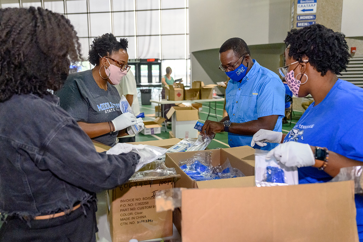 MTSU President Sidney A. McPhee, second from right, chats with volunteers Gabrielle Wilchie, Megan Roberts and Morgan Roberts on Friday, Aug. 21, on the track of Murphy Center as they help assemble 5,000 COVID-19 care packages to distribute to student residence halls, academic colleges and high traffic areas. The graduate chapter of Alpha Kappa Alpha Inc. sorority partnered with the university to create the packages, which contained sanitizing items, masks and FAQ booklets about coronavirus precautions. (MTSU photo by J. Intintoli)