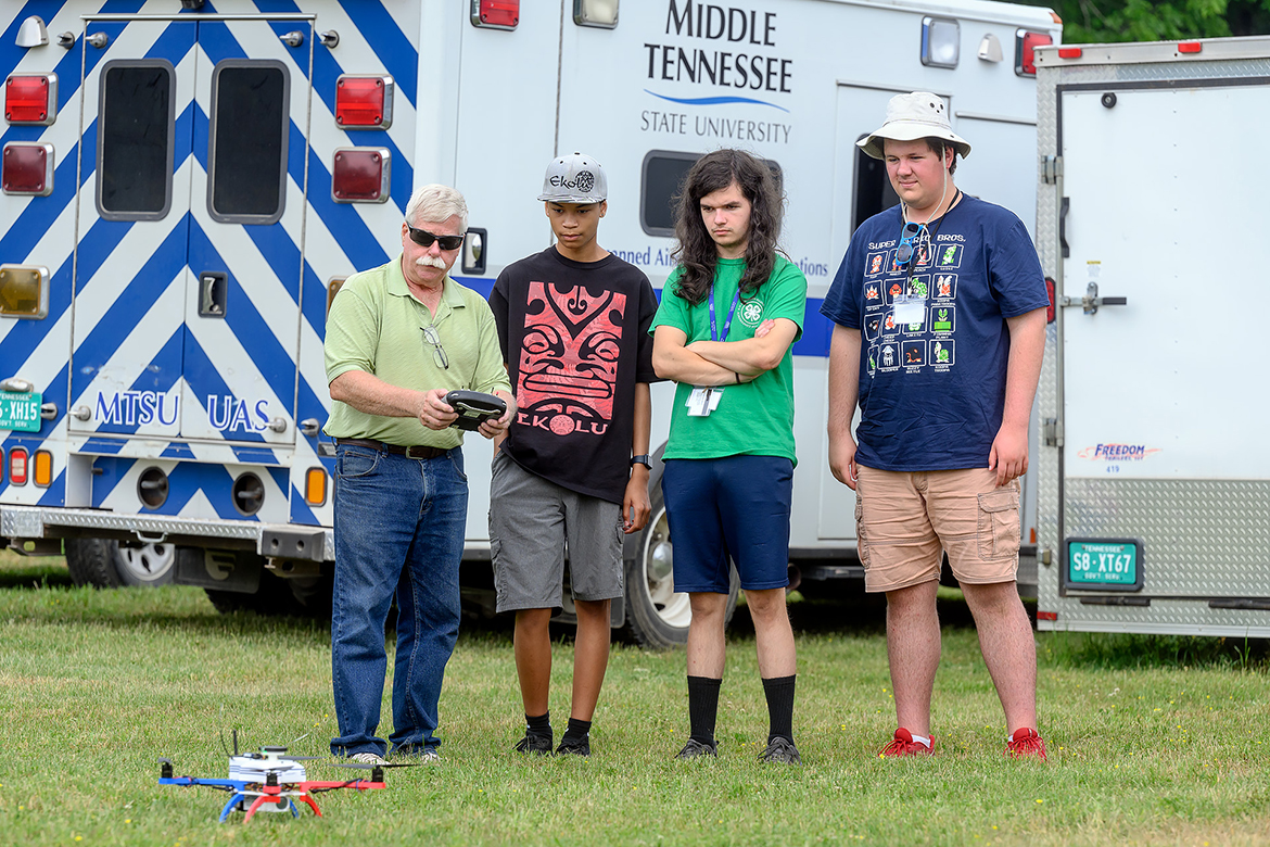 Kevin Corns, left, Middle Tennessee State University associate professor and director the Aerospace Department’s unmanned aircraft systems program, shows Digital Agriculture camp attendees Diesel Dickson, Wilson Israel and Ian Adams the right technique to fly drones at the MTSU Farm in Lascassas, Tenn. The nearly three-week camp, which wrapped up June 16, attracted 16 area high school youth interested in agriculture. (MTSU photo by J. Intintoli)