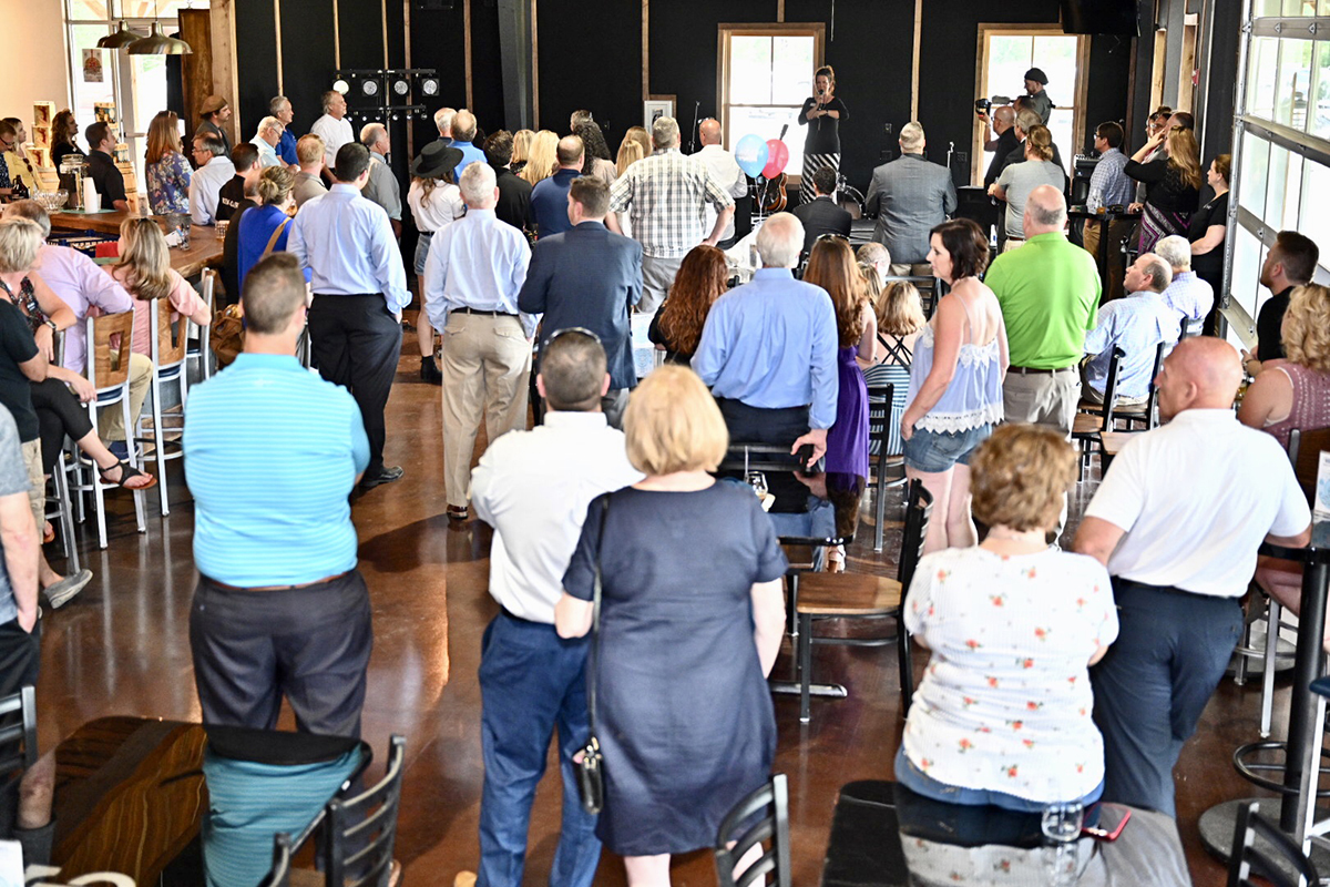 People attending the Thursday, May 23, grand opening of Hop Springs Beer Park in Murfreesboro and its partnership with MTSU fermentation science listen as Kelly Beam with the Rutherford County Chamber of Commerce talks about “one of the new jewels of the community.” About 150 invited guests took tours, participated in the ribbon-cutting ceremony and learned about an academic side to the agritourism venue. (MTSU photo by J. Intintoli)