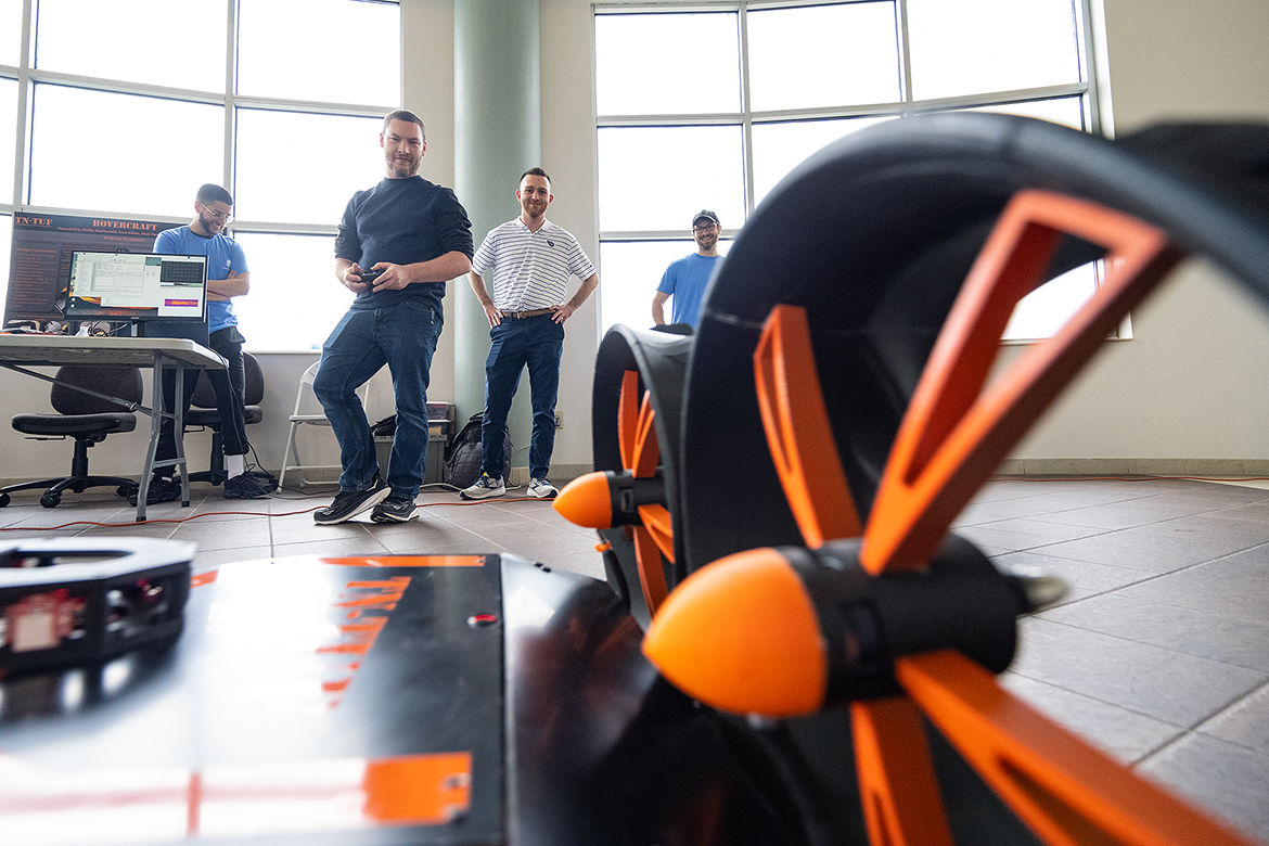 MTSU student Phillip MacDonald, second from left, of Murfreesboro, Tenn., operates the TN-TUF Hovercraft as teammates Awand Piro, left, of Nashville, Tenn., Kevin Killets of Murfreesboro and Luke Allaman of Washington, Iowa, watch during the annual Middle Tennessee State University Engineering Technology Mech-Tech expo, held on study day in the Miller Education Center second- and third-floor atriums. (MTSU photo by Cat Curtis Murphy)