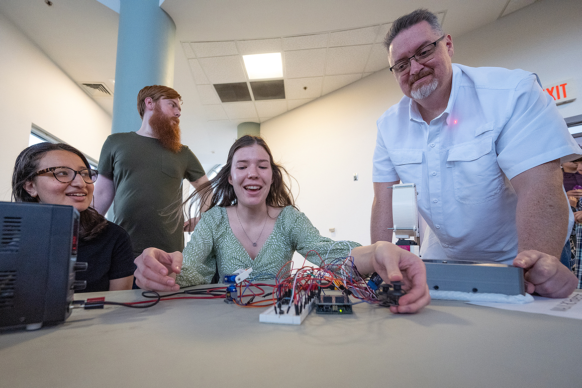 MTSU student Manal Malak of Mt. Juliet, Tenn., left, and Adam Rice, right, of Murfreesboro, Tenn., watch as Katelyn Justice of Spring Hill, Tenn., operates the MAJJK RC Hovercraft the Middle Tennessee State University Mechatronics Engineering students devised for their senior project. They and other students exhibited their projects at the annual Mech-Tech expo in the Miller Education Center second-floor atrium. (MTSU photo by Cat Curtis Murphy)