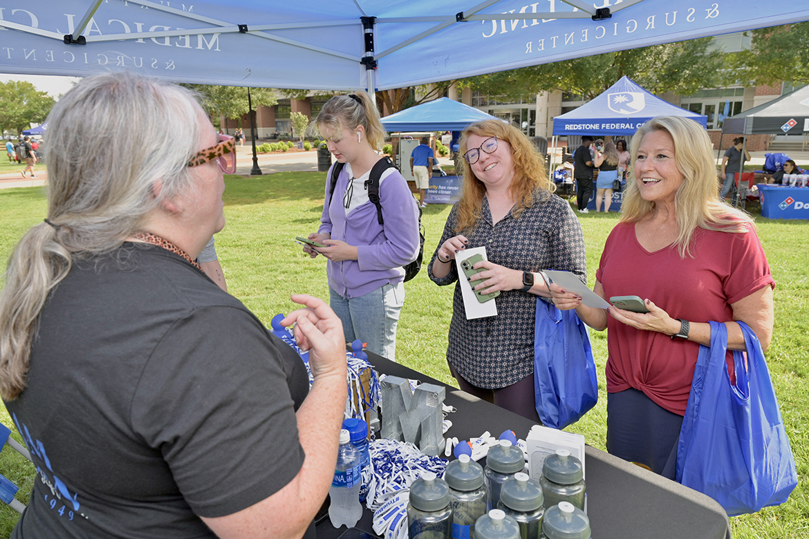 Murfreesboro Medical Clinic marketing coordinator Brandise Raikes, left, tells Middle Tennessee State University graduate studies analysts Lynsey Bennett, third from left, and Andrea Jones programs the health care company offers, as MTSU junior biology major Jessie Earwood of Murfreesboro waits to learn more during the annual New Student and Family Programs-sponsored Meet Murfreesboro event Tuesday, Aug. 29, in the Student Union Commons. (MTSU photo by Andy Heidt)
