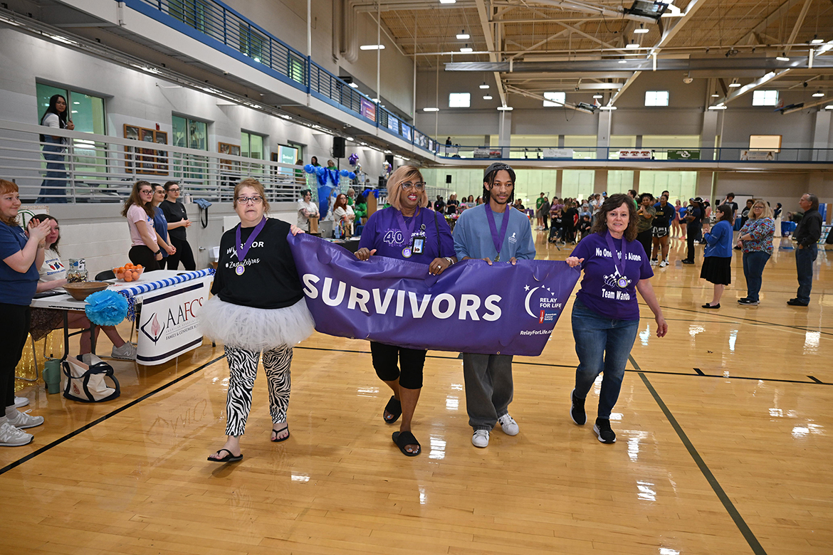 From left, volunteer Denise Bond, Middle Tennessee State University employee Flora McCullough, MTSU student and Urban Entertainment Team member Cameron Stevens and event director Dianna Rust, who is University Studies professor and Integrated Studies and Professional Studies program coordinator, carry the American Cancer Society Relay for Life “Ending Cancer” banner around the Campus Recreation Center gym floor Friday, March 28, on campus in Murfreesboro, Tenn. (MTSU photo by James Cessna)