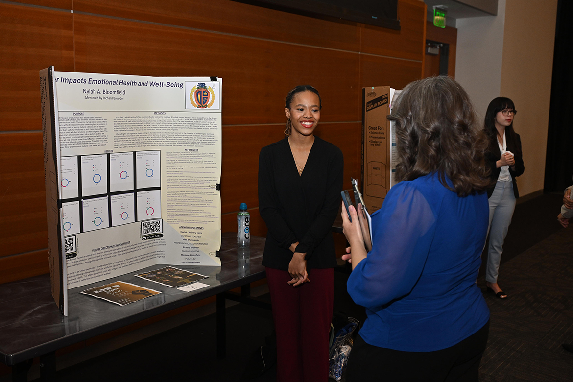 Blackman High School senior Nylah Bloomfield, left, explains her research to judge Casey Penston, coordinator in the MTSU Undergraduate Research Center, Friday, March 21, in the Student Union Ballroom on campus in Murfreesboro, Tenn., during the finale of the annual universitywide Scholars Day. Bloomfield was one of the Blackman Collegiate Academy Ready to SOAR students invited to participate this year. (MTSU photo by James Cessna)