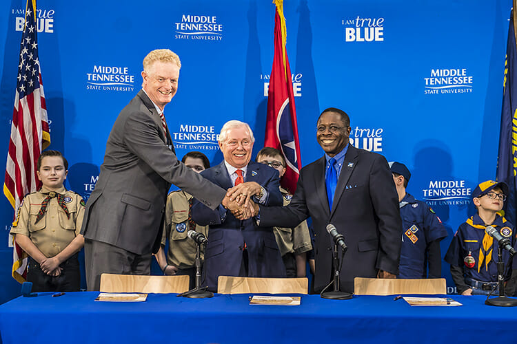 From right to left, MTSU President Sidney A. McPhee, MTSU Trustee J.B. Baker, and Larry Brown, CEO of the Middle Tennessee Council of the Boy Scouts of America, shake hands after signing a partnership Wednesday, March 7, in the Strobel Lobby at MTSU. Behind them are Cub Scouts from Scales and Rockvale elementary schools. The agreement allows the university to be a greater resource for scouting programs, particularly in science and technology. (MTSU photo by Eric B. Sutton)